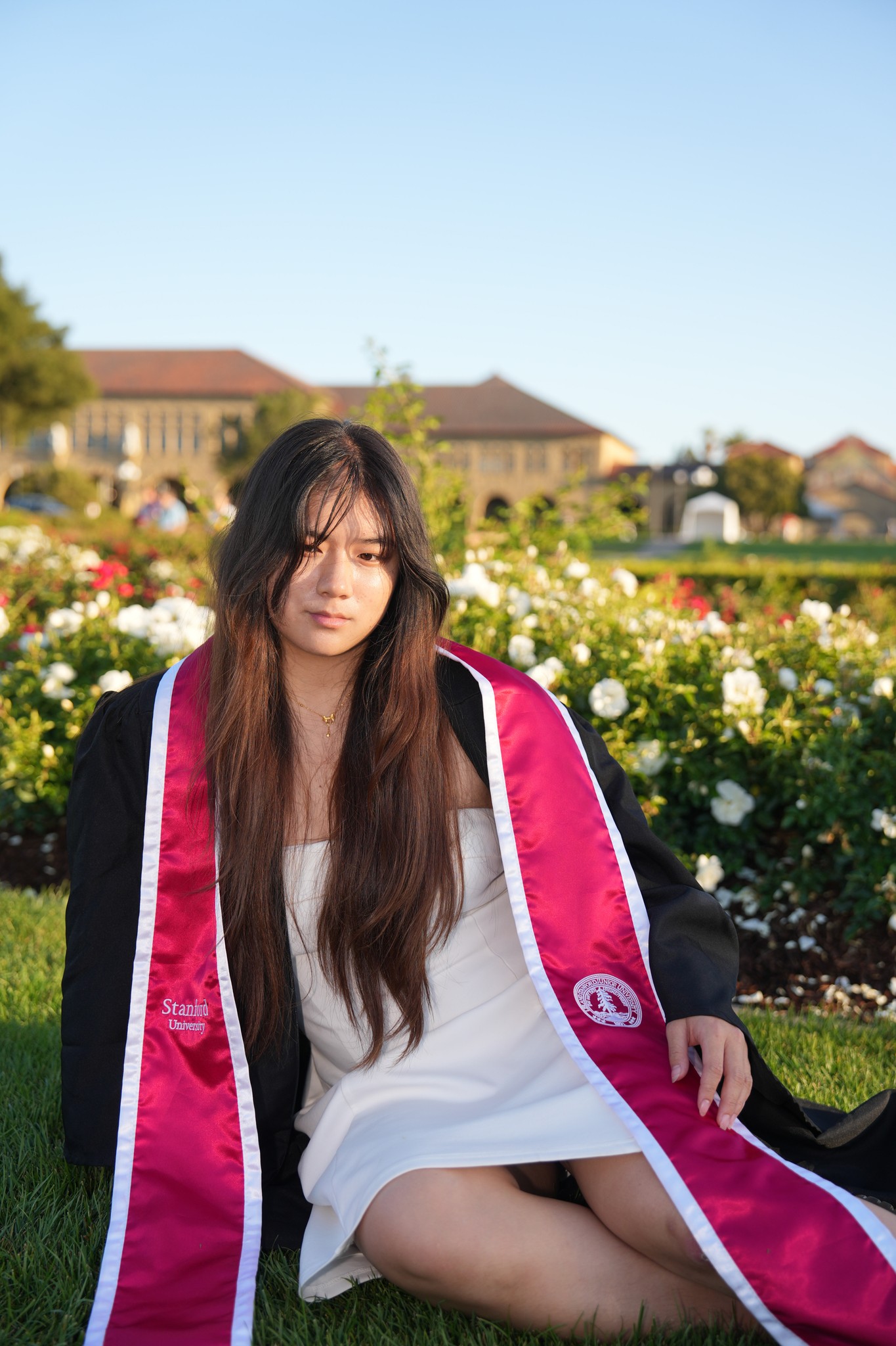 Portrait of Sherry in a graduation stole in front of a rose garden on campus