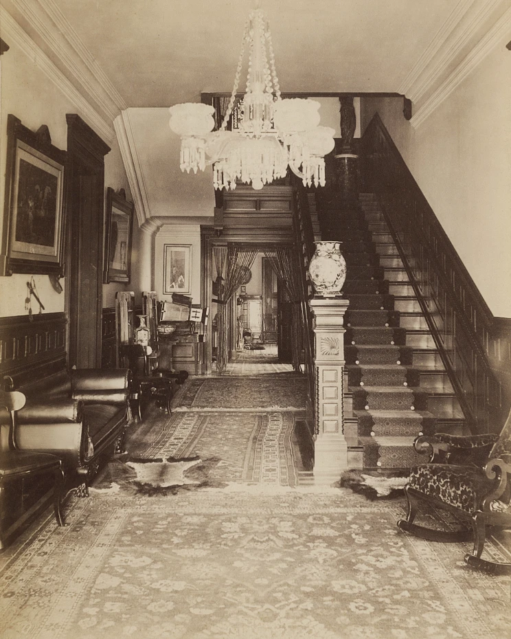 Victorian entrance hall with a crystal chandelier and carpeted staircase