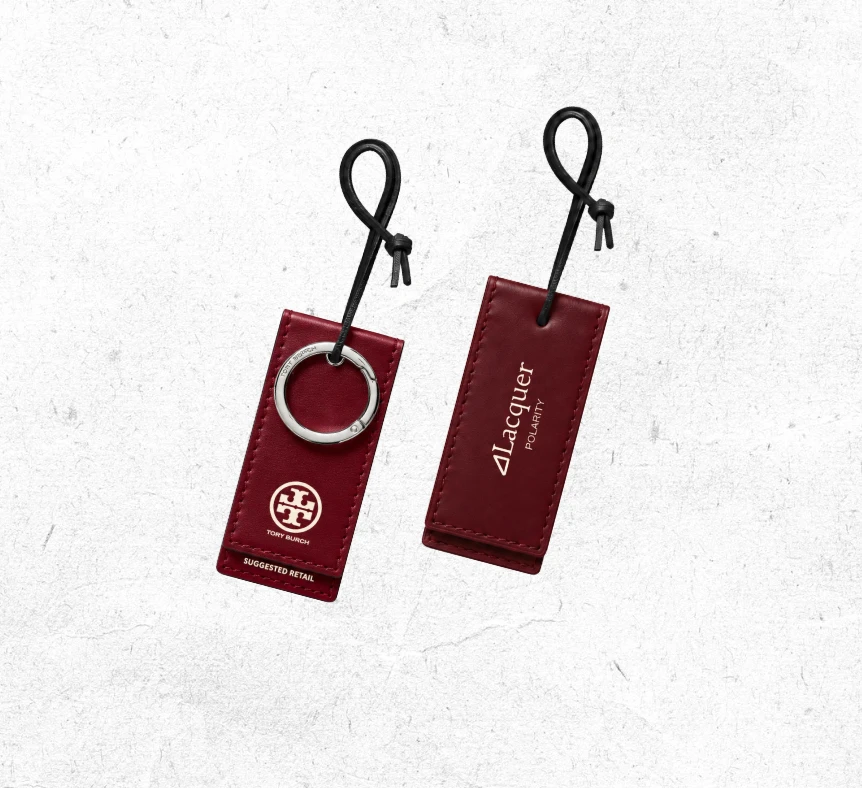 Lacquer hang tags in oxblood leather: Lacquer Polarity wordmark on one, Tory Burch logo on the other